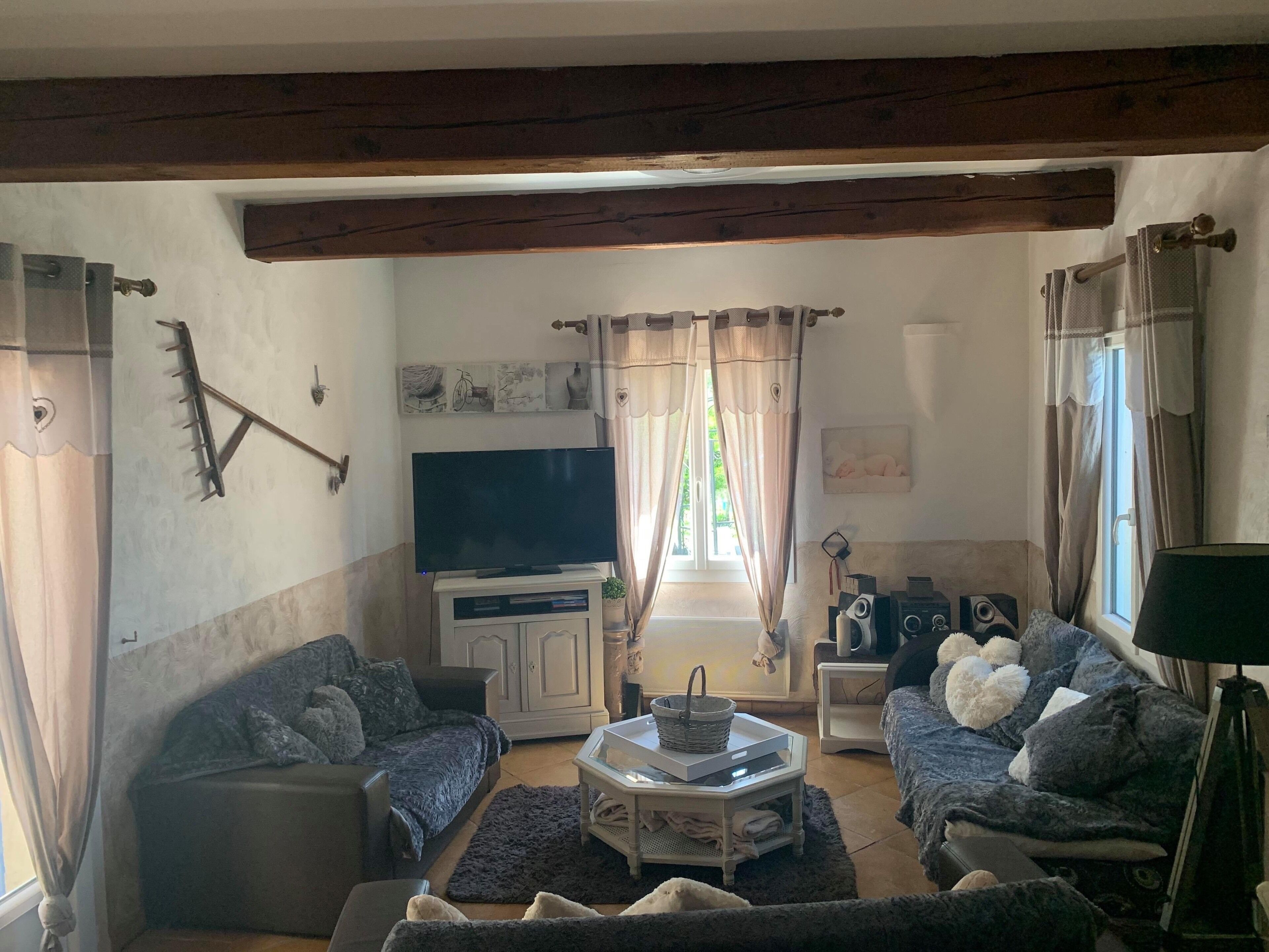 Un accogliente soggiorno con TV, due divani, un tavolino e una finestra con tende.