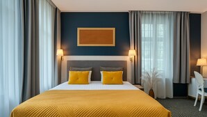 Una habitación de hotel con una cama grande, dos lámparas de noche, un escritorio y una silla.