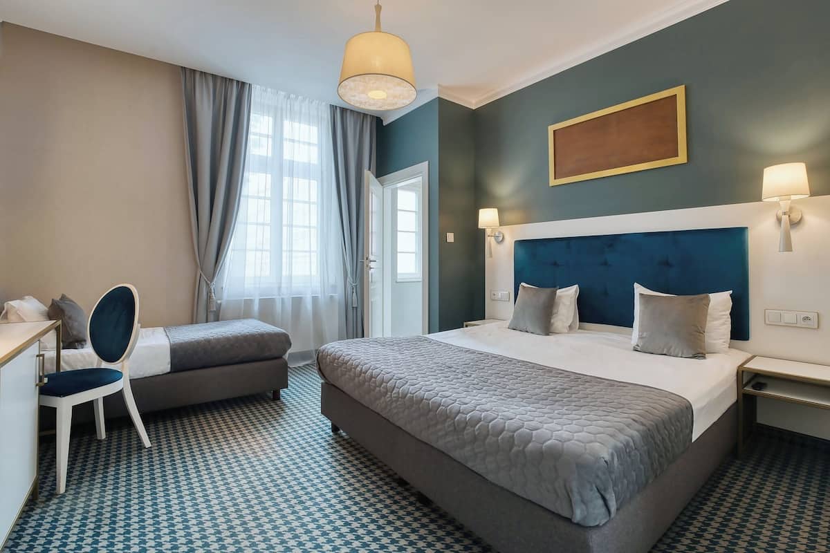 Una habitación de hotel con cama, escritorio, silla y vistas al exterior.