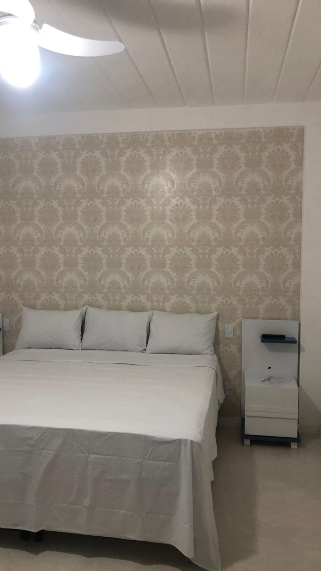 A bedroom with a bed, a nightstand, and a ceiling fan.