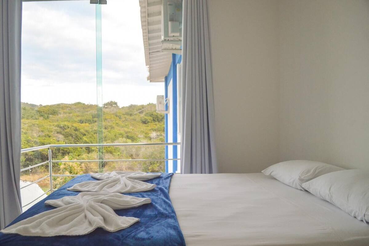 Une chambre d’hôtel avec un lit, une vue sur la verdure et un balcon doté d’une balustrade.