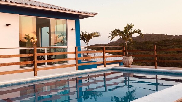 Ein modernes Gebäude mit Pool, Holzterrasse und Palmen.