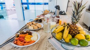 Ein reichhaltiges Frühstücksbuffet mit verschiedenen Früchten, Gebäck und Getränken auf einer Marmortheke.