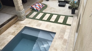 A pool area with a stone deck, a small garden with stepping stones, and outdoor seating.