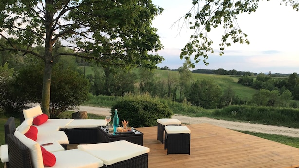 An outdoor deck with wicker furniture, a bottle, and snacks.