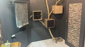 A bathroom with a towel rack, a wooden cabinet, a stone wall, and a tiled floor.