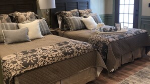 A bedroom with two queen beds, a large window, and a wooden floor. - Guest Quarters at the Inn  - 102 (North Beach)