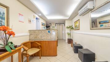 A reception area with a wooden desk, a chair, a counter, and a potted plant.