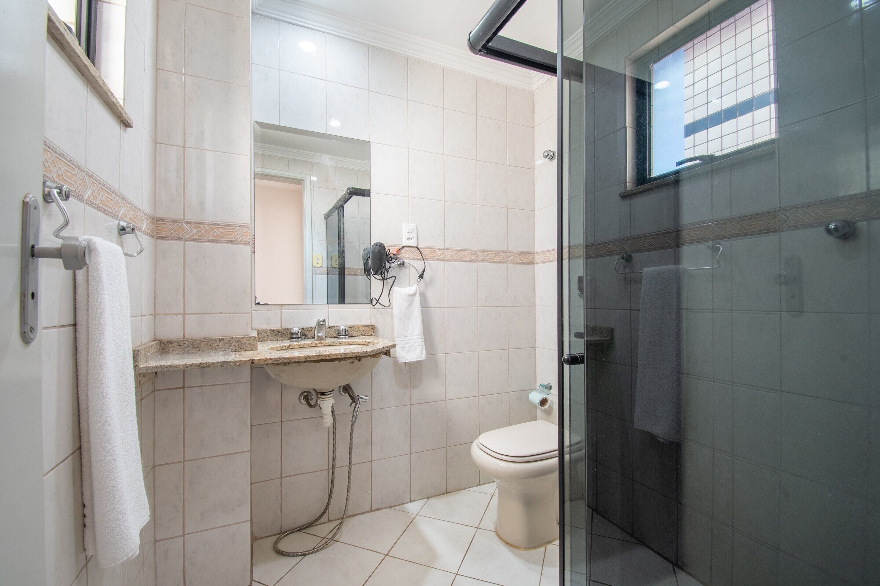 Un baño con cabina de ducha de vidrio, lavabo con espejo e inodoro.