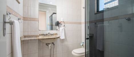 Un baño con cabina de ducha de vidrio, lavabo con espejo e inodoro.