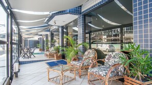 A hotel patio with wicker furniture, potted plants, and a tiled floor.