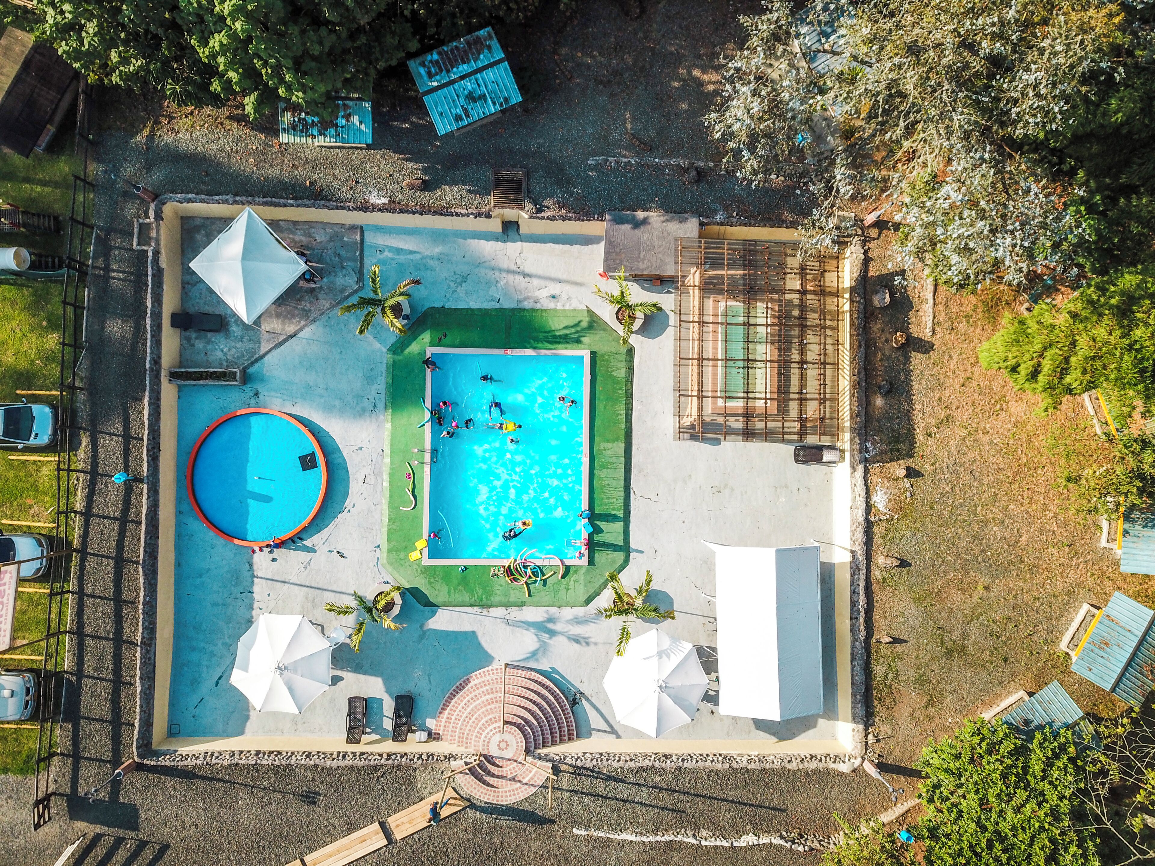 Una piscina al aire libre, sombrillas, sillones reclinables de piscina