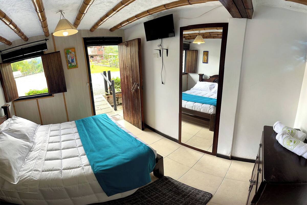 Une chambre à coucher avec un lit, une télévision, une porte en bois et une fenêtre.
