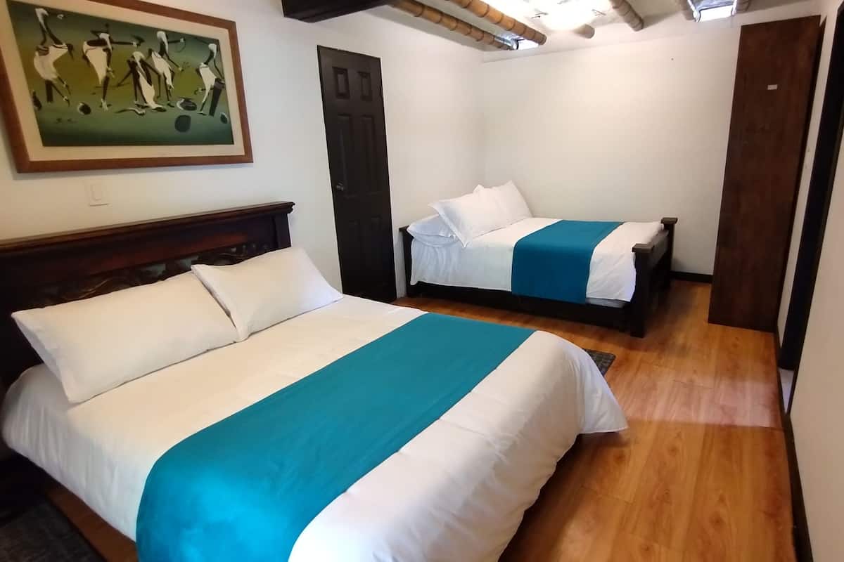 Une chambre d’hôtel avec deux lits, un tableau au mur et un plancher en bois.