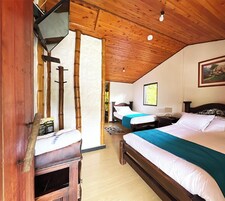A wooden room with two beds, a desk, and a window.