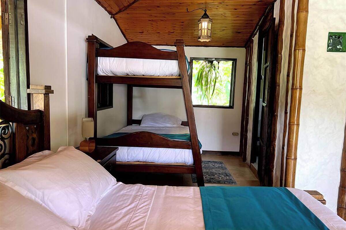 Une chambre avec un lit superposé, un bureau et une fenêtre donnant sur un paysage verdoyant.