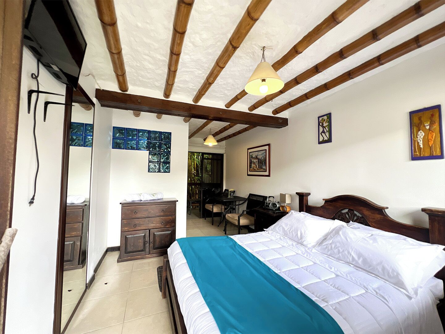 A bedroom with a bed, wooden ceiling beams, a desk, and a chair.