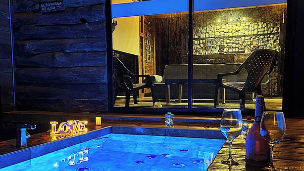 Uma área de piscina com deck de madeira, uma vela e uma cadeira.