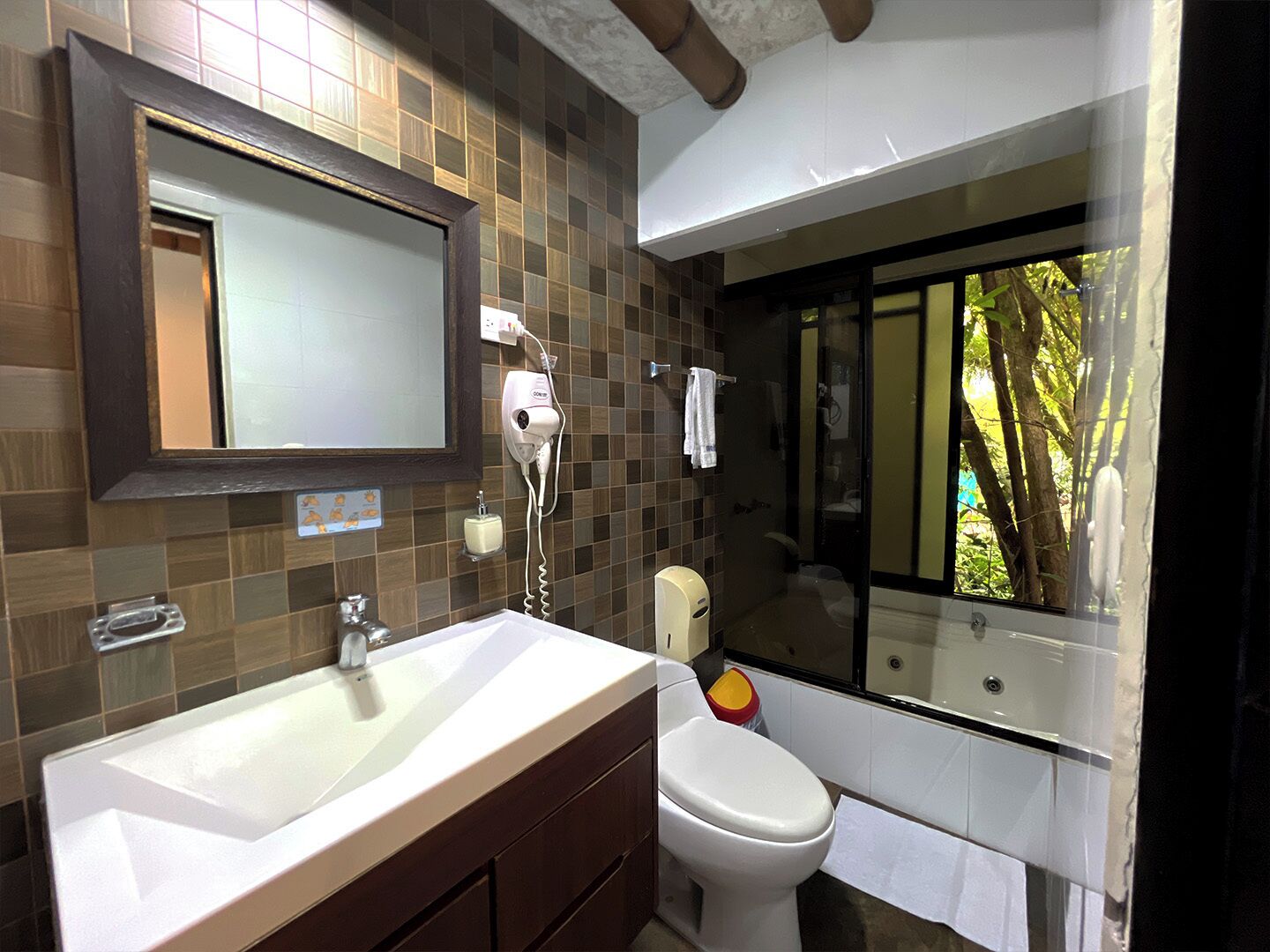 A bathroom with a large mirror, a sink, a toilet, and a shower area.