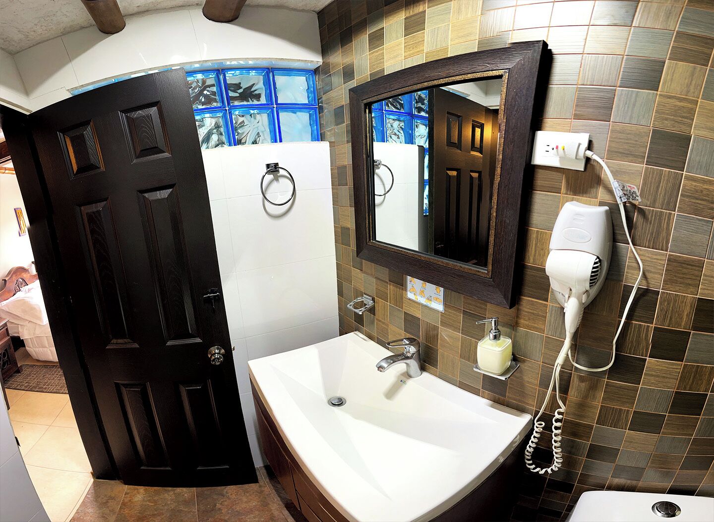 A bathroom with a white sink, a hairdryer, and a mirror.