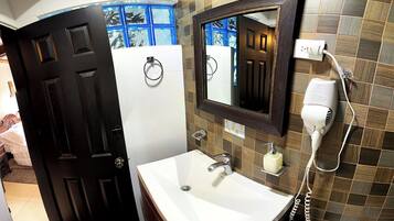 Un baño con lavamanos blanco, secador de pelo y espejo.