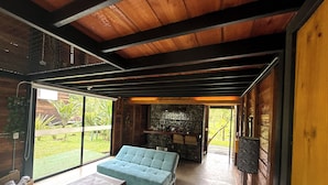 Um interior moderno com um sofá azul, uma mesa pequena e um bar com parede de pedra.