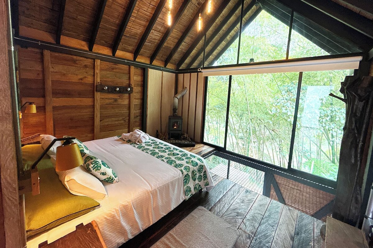 Une chambre confortable avec un lit, une table de chevet, une lampe et une grande fenêtre.