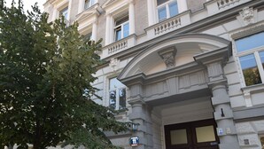 A historic building with a stone facade, a central entrance with a decorative arch, and a motorcycle parked in front. - Elegant Apartament Copernicus (Warsaw)