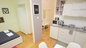 A compact room with a bed, a small kitchenette, a dining table, and a chair. - Elegant Apartament Copernicus (Warsaw)