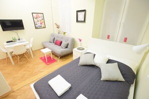 A modern bedroom with a bed, a desk, a sofa, and a TV. - Elegant Apartament Copernicus (Warsaw)