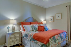 Un dormitorio con cama, mesita de noche, lámpara y adornos en la pared.