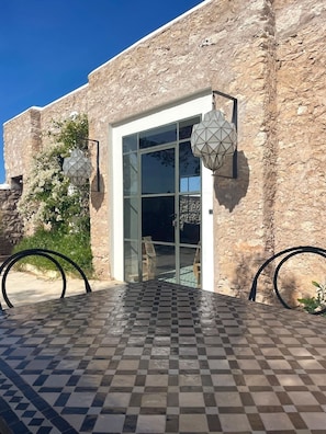 A building with a stone facade, a glass door entrance, and a tiled patio area.