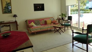 Ein Wohnzimmer mit einer Couch, Stühlen, einem Esstisch und einem großen Fenster.
