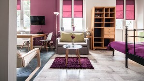 Une chambre moderne comprenant un lit, un bureau, une chaise, un canapé, une bibliothèque et un téléviseur.