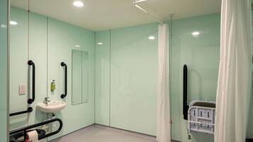 A hospital room with a bed, a sink, a mirror, and a curtain.