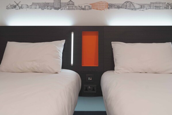 A hotel room with two beds, a modern headboard, a cityscape mural, and a built-in orange shelf. - easyHotel Milton Keynes (Milton Keynes)