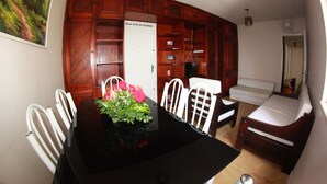 Una habitación compacta con una mesa de comedor, sillas, un sofá y una cama.