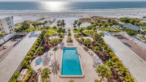 Un complexe hôtelier doté d’une piscine centrale, de palmiers et offrant une vue sur la plage.
