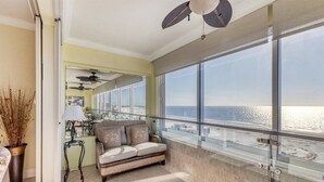 Un balcon avec vue sur l’océan, un canapé et un coin repas avec une table et des chaises.
