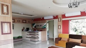 A reception area with a desk, a sofa, and a staircase leading to another floor. - SKD Amar Bari a Luxury Resort (Sreemangal)