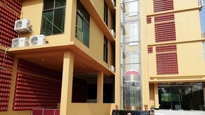 A building with a yellow facade, air conditioning units, a staircase, and a signboard. - SKD Amar Bari a Luxury Resort (Sreemangal)