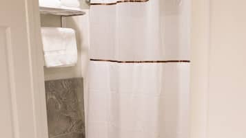 Un baño con inodoro, cortina de ducha y toallero con toallas dobladas.