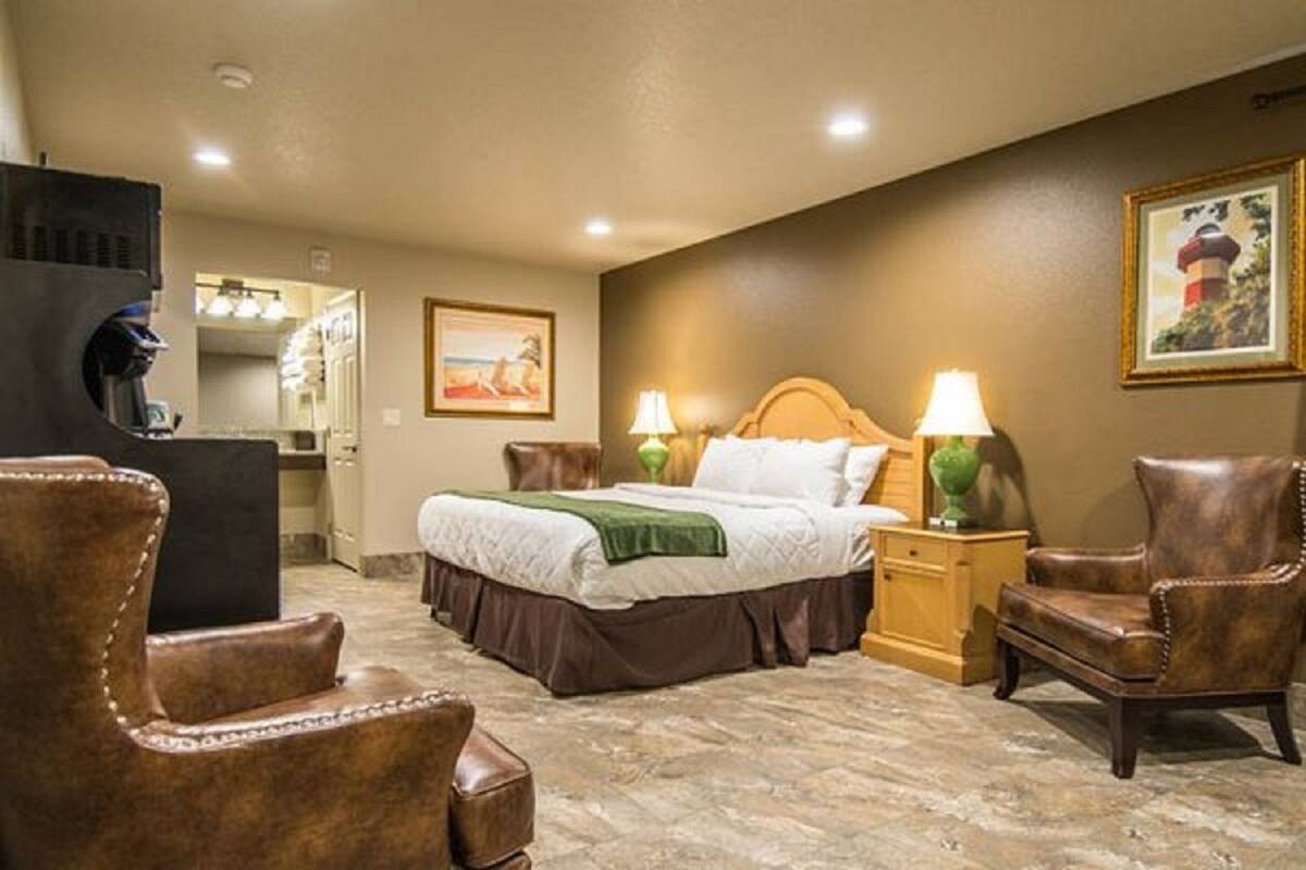 A hotel room with a bed, two nightstands with lamps, a chair, a desk, and a mirror.