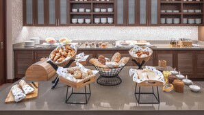 Un buffet de petit-déjeuner proposant un assortiment de viennoiseries, de pains et de condiments.