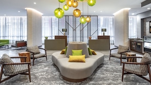 Un hall d’entrée moderne avec un canapé aux lignes courbes, des fauteuils en osier et un mur orné de motifs.