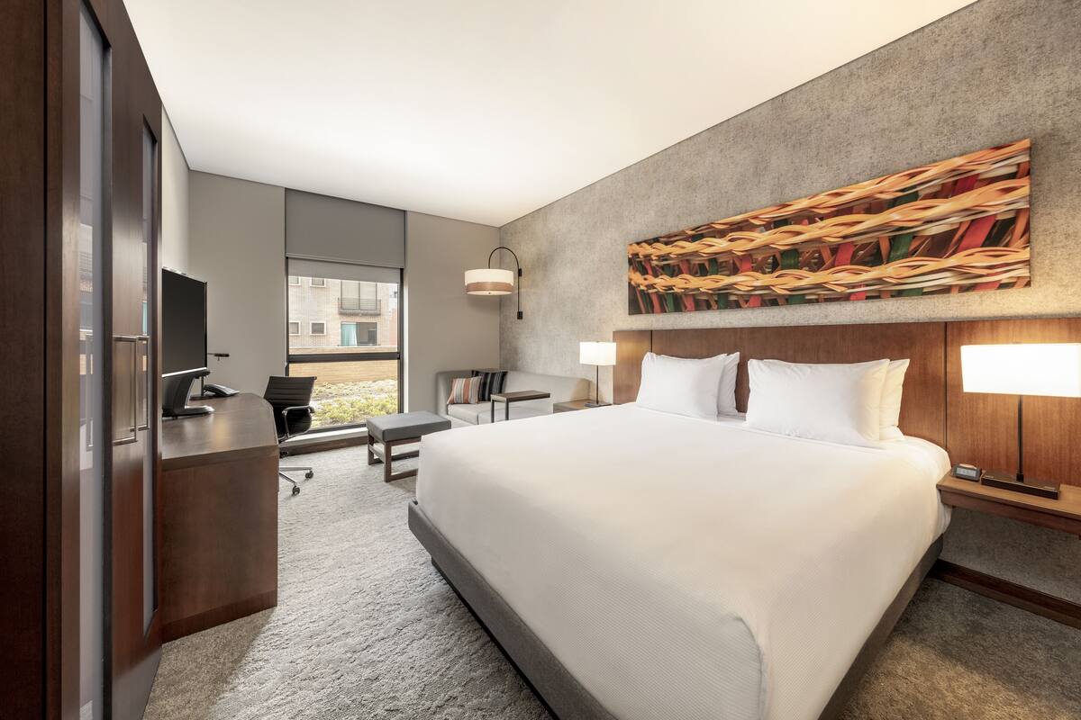 Habitació d'hotel moderna amb un llit gran, un escriptori, una cadira i una televisió.