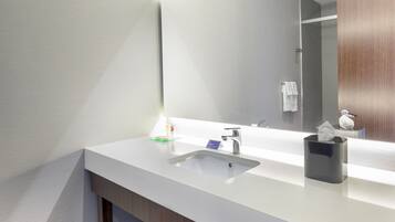 A modern bathroom with a white sink, a mirror, and a wooden vanity.