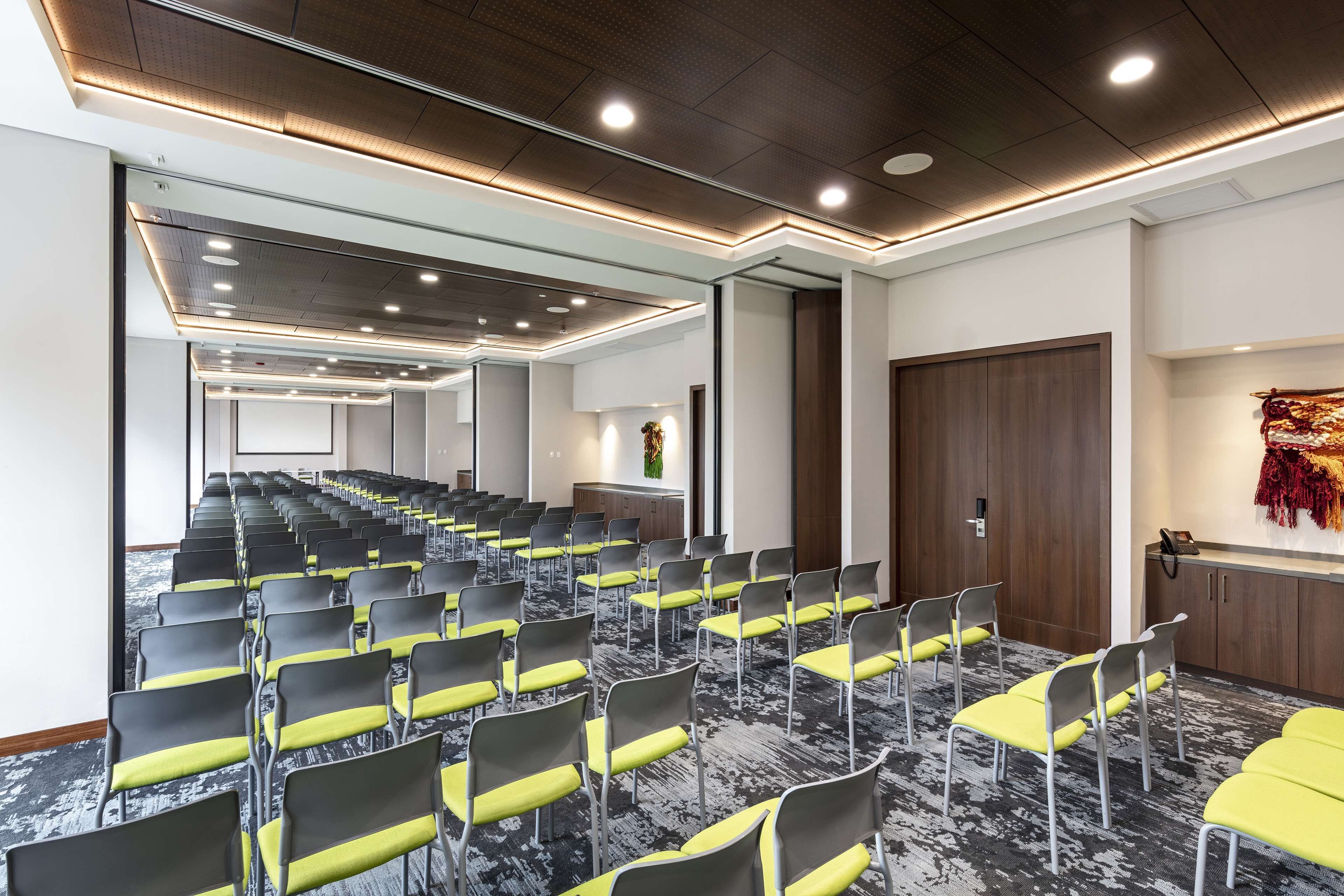 A conference room with rows of chairs, a reception desk, and a wooden door.