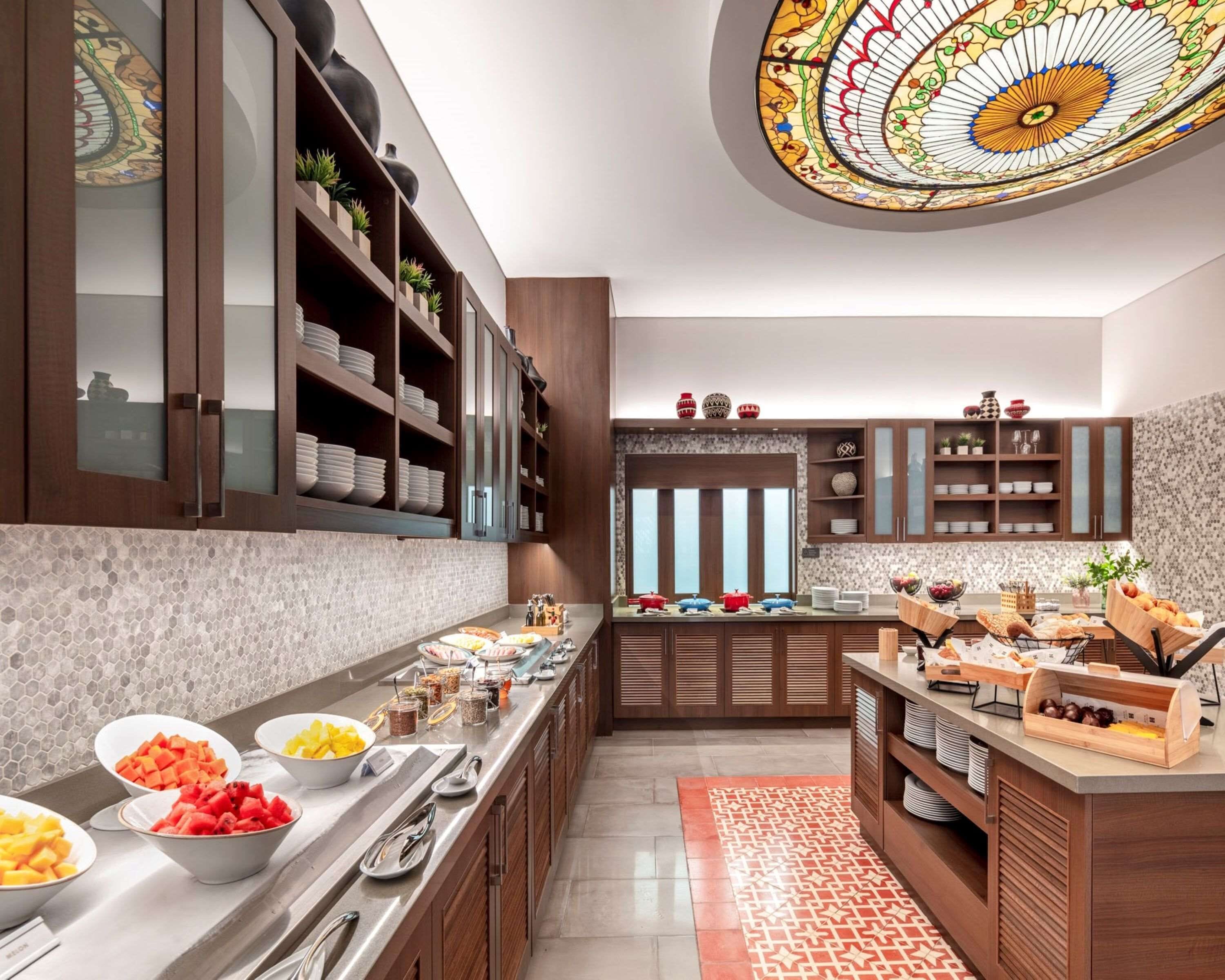 A modern kitchen with a breakfast bar, wooden cabinets, and a decorative ceiling.