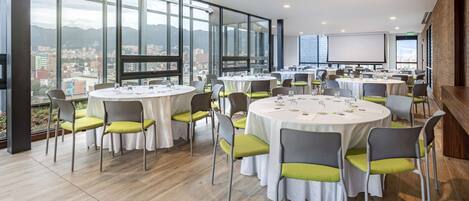 A conference room with round tables, chairs, and a large screen.